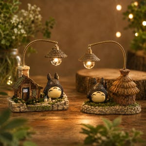May include: Two decorative lamps featuring a cartoon character, each with a small house and a lamp post. The lamps have a warm, inviting glow, and the bases are detailed with miniature scenery. The word "TOTORO" is visible on one base.