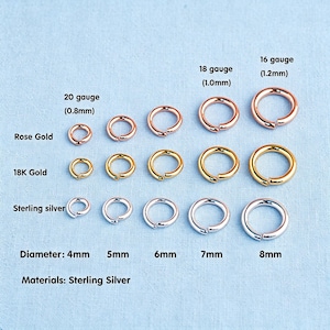 Op de afbeelding: Een collectie springringen in roségoud, 18K goud en sterling zilver. De ringen zijn gerangschikt in een raster op diameter van 4mm tot 8mm en dikte van 20 gauge (0,8mm) tot 16 gauge (1,2mm). Tekstlabels geven de materialen en maten aan.