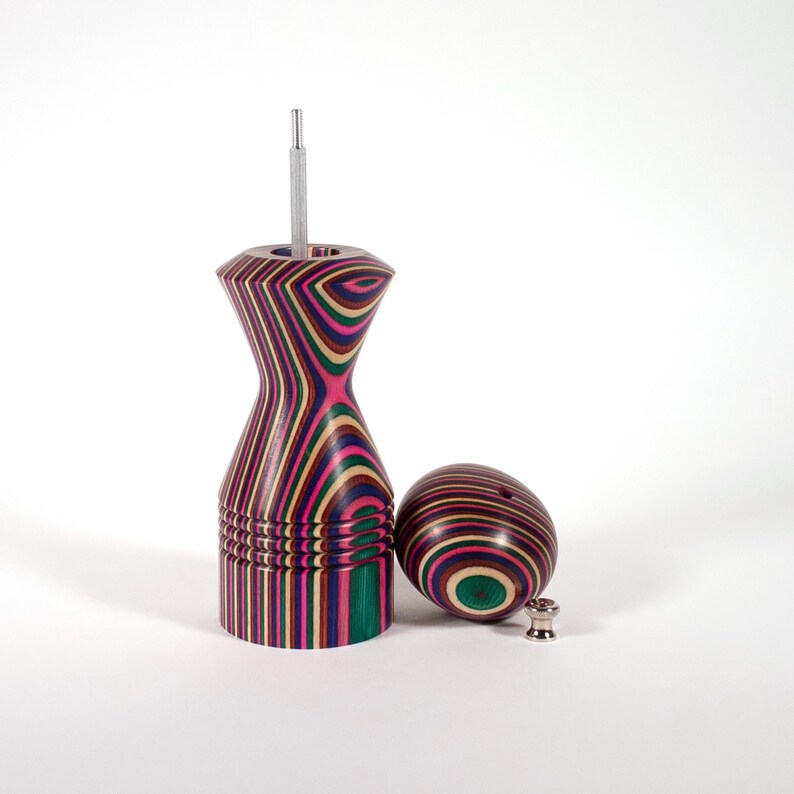 Puede incluir: Un juego de salero y pimentero de madera colorido con un dise&ntilde;o a rayas. Los saleros est&aacute;n hechos de madera con una variedad de colores, incluyendo rosa, verde, azul y marr&oacute;n. Los saleros est&aacute;n separados y la parte superior del pimentero est&aacute; abierta, revelando un molinillo de pimienta plateado.