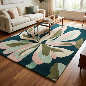 May include: A large, rectangular area rug with a floral design. The rug features a dark teal background with a large, stylized flower in shades of pink, green, and cream. The rug is placed on a hardwood floor in a living room setting.