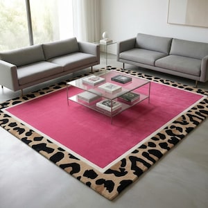 May include: A modern living room setup featuring two gray sofas, a glass coffee table, and a vibrant pink rug. The rug has a leopard print border and a white inner border. Books and decorative items are on the table.