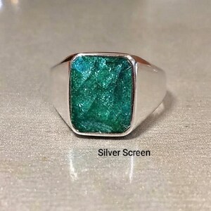 Op de afbeelding: Een zilveren zegelring met een rechthoekige, gefacetteerde, diepgroene steen in het midden. De metalen band is glad en gepolijst en reflecteert het licht. De tekst Silver Screen staat in het zwart onder de ring afgedrukt.