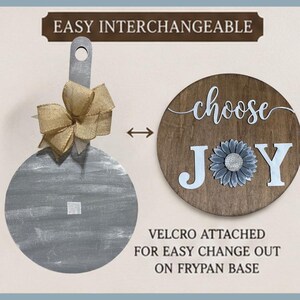 May include: A gray wooden frypan-shaped base with a burlap bow and a circular wooden sign featuring the text choose JOY with a sunflower icon. The text EASY INTERCHANGEABLE and VELCRO ATTACHED FOR EASY CHANGE OUT ON FRYPAN BASE are visible.