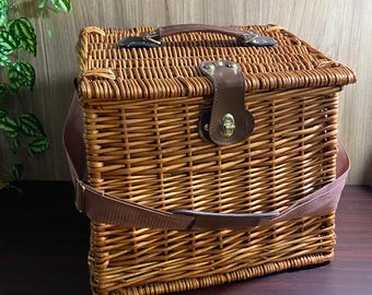 Vintage rieten picknickmand voor 2 personen met borden, glazen en bestek, gevoerd met geruite stof.