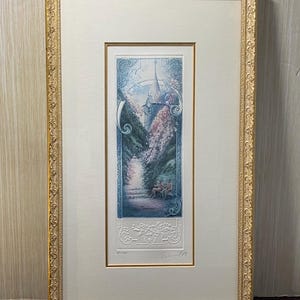 Peut inclure: Impression d'art encadrée représentant un paysage détaillé avec un bâtiment et des personnages sur un banc. L'impression est encadrée dans un cadre doré orné et un passe-partout blanc. L'œuvre représente un chemin avec des arbres et des fleurs.