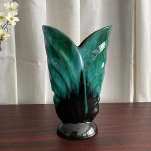 Peut inclure: Une tasse en céramique blanche avec une anse noire et le texte "But First, Coffee" en gras noir. La tasse est remplie d'un liquide foncé, probablement du café, et posée sur une surface claire.