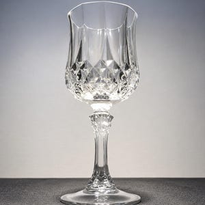 Peut inclure: Un verre à pied en cristal transparent présentant un motif à facettes en losange sur la partie inférieure du calice. La tige est ornée d'un design texturé à facettes multiples menant à une base circulaire lisse. Le bord est festonné.