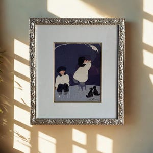 Peut inclure: Une illustration encadrée montrant deux personnages en haut blanc et bas sombre, l'un assis et l'autre debout sur un petit tabouret, sous un croissant de lune et un ciel étoilé. Deux chats noirs sont assis. L'œuvre est dans un cadre argenté orné.