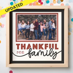 May include: A square wooden frame containing a photograph of a large group of people standing outdoors. Below the photo, the text reads "THANKFUL FOR family" in a combination of bold block letters and a black cursive script font.