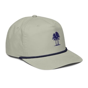 Könnte beinhalten: Eine hellgraue Baseballkappe mit einer dunkelblauen Stickerei von drei Kiefern auf der Vorderseite. Die Kappe verfügt über eine dunkelblaue Zierkordel an der Basis der Krone, direkt über dem steifen, flachen Schirm.