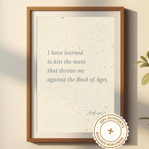 May include: A framed print with a light beige background and a brown wooden frame. The print features the quote, "I have learned to kiss the wave that throws me against the Rock of Ages." A circular sticker at the bottom reads "10% Supports Missions Worldwide."