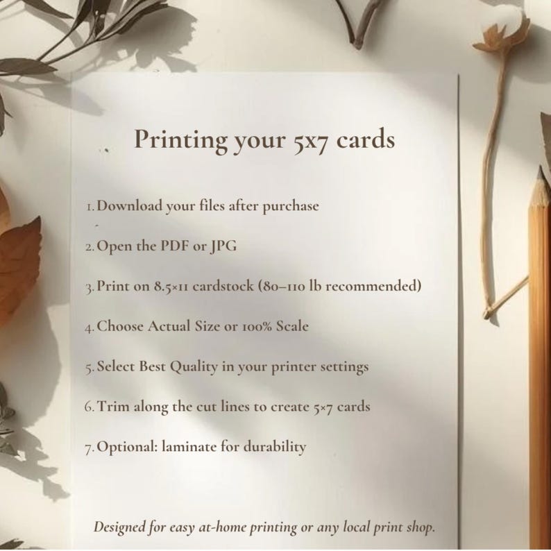 May include: A white sheet of paper with instructions for printing 5x7 cards. The text includes steps for downloading files, opening PDFs, printing on 8.5x11 cardstock, and trimming. The paper is surrounded by dried leaves and a pencil.