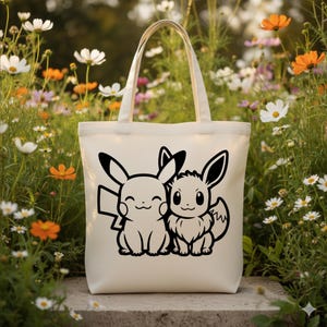 May include: Cream-colored tote bag featuring a black graphic of Pikachu and Eevee. The bag has two handles and is set against a backdrop of colorful flowers. The design is simple and bold, perfect for carrying everyday items.