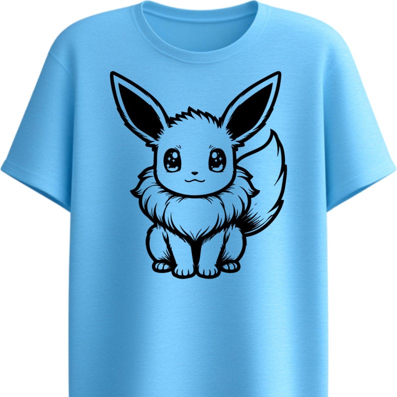 May include: Light blue t-shirt featuring a black and white cartoon illustration of a creature with large ears and a fluffy tail. The graphic is centered on the front of the shirt. The shirt has a crew neck and short sleeves.