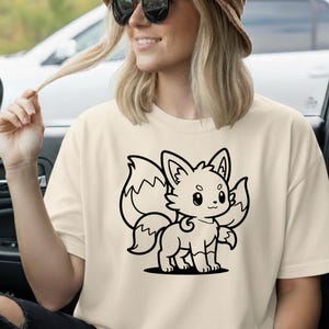 May include: Cream-colored t-shirt featuring a black cartoon fox design. The fox has large ears, a fluffy tail, and a friendly expression. The shirt is a casual style, suitable for everyday wear.