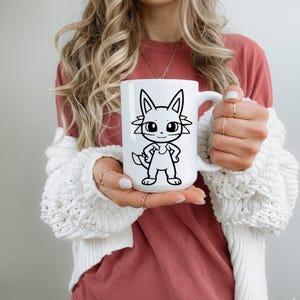 May include: White ceramic mug featuring a black and white cartoon cat design. The cat has large eyes and is standing with its hands on its hips. The mug has a large handle and is held by a person.