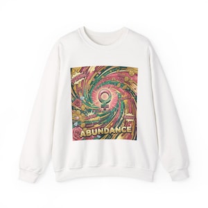 May include: White crewneck sweatshirt featuring a colorful graphic with a female symbol at the center. The design includes the word "ABUNDANCE" and other words like "SPARKLE" and "BLOOM". The graphic has a swirling, vibrant design.