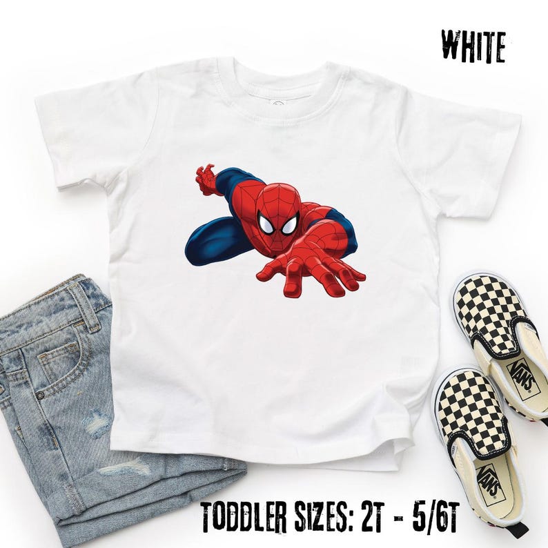 May include: A white short-sleeved t-shirt featuring a graphic of the character Spider-Man in a crouching pose. The shirt is labeled as white and available in toddler sizes 2T through 5/6T. The design shows the character in red and blue.