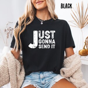 May include: Black t-shirt with the white text "JUST GONNA SEND IT". The shirt is a crew neck style. The word "BLACK" is printed in white in the upper right corner of the image.