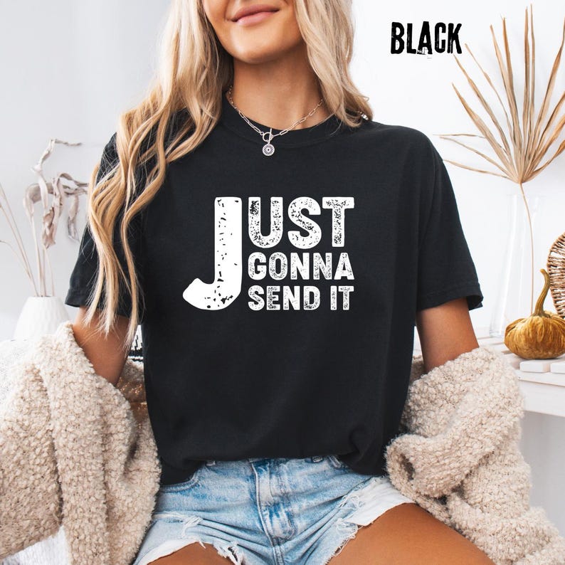 May include: Black t-shirt with the white text "JUST GONNA SEND IT". The shirt is a crew neck style. The word "BLACK" is printed in white in the upper right corner of the image.