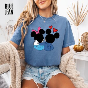 May include: Blue jean short-sleeved t-shirt featuring a graphic of two cartoon mice embracing, with red heart accents. One mouse has a pink bow. The text "BLUE JEAN" is printed in black block letters in the upper left corner.