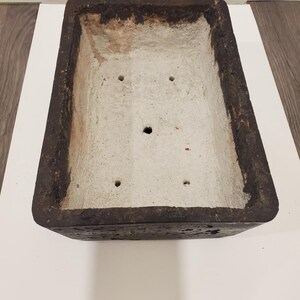 K&ouml;nnte beinhalten: Rechteckiger, verwitterter Pflanzk&uuml;bel mit dunkelbrauner Au&szlig;enseite und hellgrauer Innenseite. Der Pflanzk&uuml;bel hat Abzugsl&ouml;cher und ist f&uuml;r verschiedene Pflanzen geeignet. Die raue Textur verleiht einen rustikalen Charme.