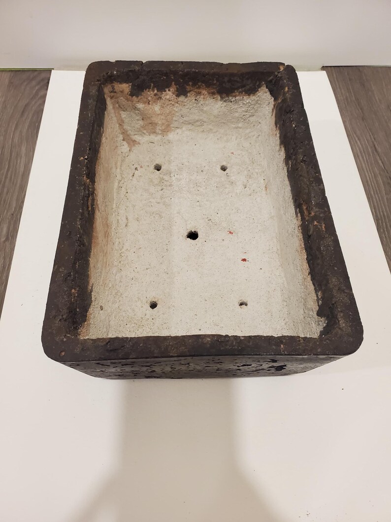 K&ouml;nnte beinhalten: Rechteckiger, verwitterter Pflanzk&uuml;bel mit dunkelbrauner Au&szlig;enseite und hellgrauer Innenseite. Der Pflanzk&uuml;bel hat Abzugsl&ouml;cher und ist f&uuml;r verschiedene Pflanzen geeignet. Die raue Textur verleiht einen rustikalen Charme.