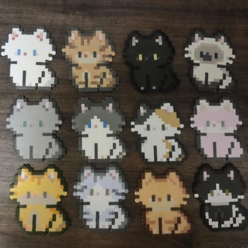 May include: A collection of twelve pixelated cat designs in various colors. The cats are in a sitting position, with details like blue eyes and patterned fur. The color palette includes white, black, gray, orange, and calico patterns.