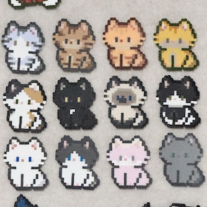May include: A selection of pixel art cat designs in a variety of colours, including grey, brown, orange, yellow, black, white, and pink. Each cat is shown sitting with detailed pixelated features.