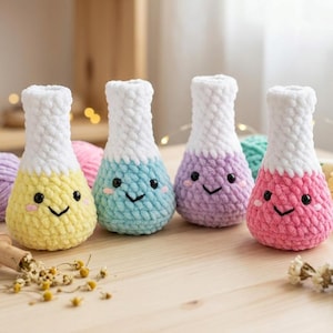 Peut inclure: Quatre peluches crochetées en forme de fioles de laboratoire, chacune avec une partie supérieure blanche et une base colorée en jaune, bleu clair, violet ou rose. Chaque fiole a deux yeux en perles noires, un sourire brodé et des joues roses.