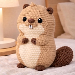 May include: A handmade crochet beaver plushie. The plush toy features a light brown body with a cream-colored belly, dark brown accents, and a flat tail. It has black safety eyes and a small white tooth.