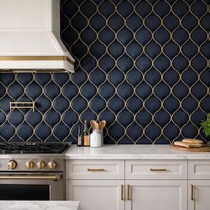 Puede incluir: Una cocina moderna con un salpicadero de azulejos azul marino con un patrón geométrico dorado. La cocina incluye una campana extractora blanca con ribete dorado, una estufa de acero inoxidable y armarios blancos con herrajes dorados.