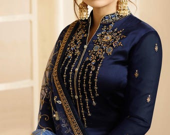 May include: A dark navy blue long-sleeved tunic featuring intricate gold and blue floral embroidery along the neckline and cuffs. The garment is paired with a sheer light blue dupatta with gold embroidery and gold-toned dangling earrings.