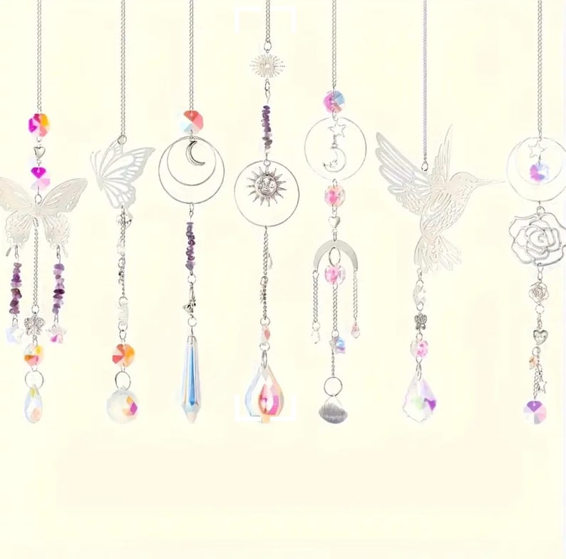 May include: Seven hanging suncatchers featuring silver-toned metal charms including butterflies, a hummingbird, a rose, a sun, and moons. Each ornament is suspended by a silver chain and decorated with colorful glass beads and clear crystal prisms.