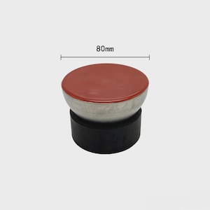May include: A three-part object with a red top, a silver-colored middle section, and a black base. The top is 80mm in diameter. The object appears to be a stopper or a decorative element.