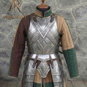 May include: A silver-colored metal breastplate and leg armor set with intricate designs, displayed on a mannequin. The armor is paired with a quilted brown, tan, and green undergarment. The image includes the text "ARMORIST".