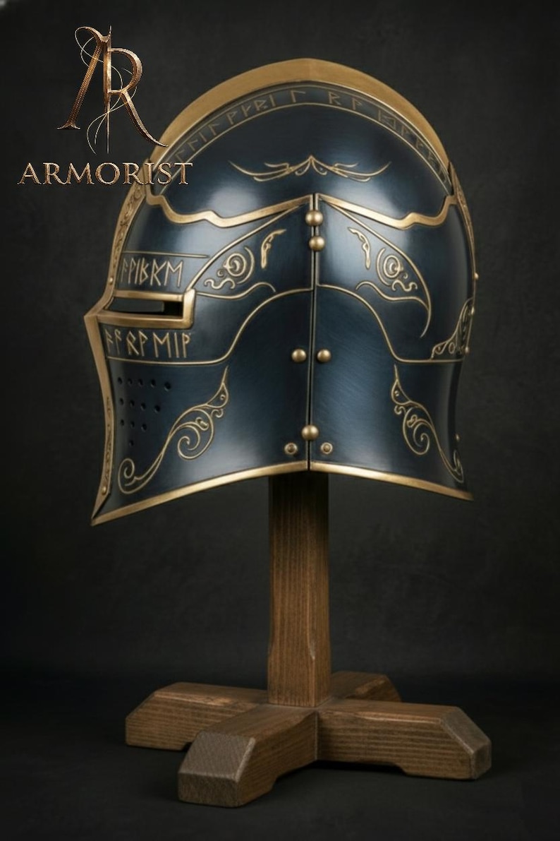 K&ouml;nnte beinhalten: Dunkelblauer und goldener mittelalterlicher Helm mit aufwendigen goldenen Details und dem Wort "ARMORIST" in der oberen linken Ecke. Der Helm wird auf einem Holzst&auml;nder vor dunklem Hintergrund ausgestellt.