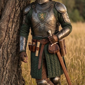K&ouml;nnte beinhalten: Ein mittelalterlicher Ritter in voller R&uuml;stung steht neben einem Baum in einem Feld. Die R&uuml;stung ist silber und gr&uuml;n, mit Helm, Brustplatte und Beinsch&uuml;tzern. Der Ritter tr&auml;gt eine gr&uuml;ne Tunika, einen braunen Lederg&uuml;rtel und ein Schwert. Der Text "ARMORIST" ist enthalten.