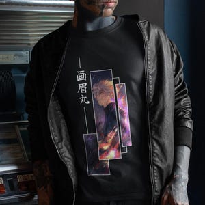 Może przedstawiać: Czarny t-shirt z grafiką przedstawiającą osobę i japoński tekst. Grafika ma prostokątny kształt w kolorach fioletowym i pomarańczowym. Osoba ma na sobie czarną skórzaną kurtkę.