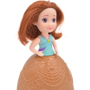 Puede incluir: Una pequeña muñeca con cabello rojo, que lleva una blusa turquesa y morada y una falda marrón. La muñeca tiene una cara sonriente y está sobre un fondo blanco. La falda tiene un patrón detallado.
