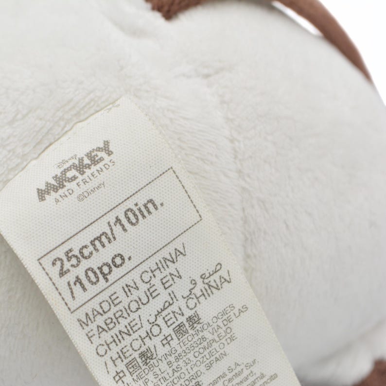 May include: A white plush toy with a tag that reads "MICKEY AND FRIENDS" and "25cm/10in." The tag also indicates the toy was made in China. The toy has a soft, textured appearance.