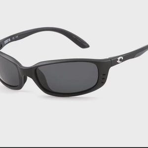 Puede incluir: Gafas de sol negras con lentes oscuras. Las gafas tienen una montura curvada y la marca "COSTA" es visible en la patilla izquierda. El logotipo de Costa est&aacute; en la patilla derecha.