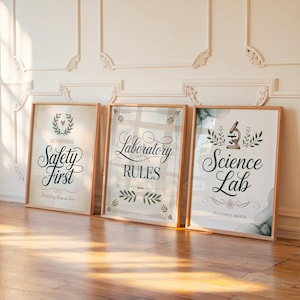 May include: Three framed prints with wooden frames leaning against a wall. The prints feature text: "Safety First", "Laboratory Rules", and "Science Lab". The "Science Lab" print includes a microscope illustration. The prints have a vintage aesthetic.