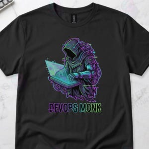 May include: Black t-shirt featuring a digital illustration of a hooded figure operating a laptop. The figure is rendered in shades of purple, blue, and green, with the text "DevOps Monk" below. The shirt is from Layer 8 Apparel.