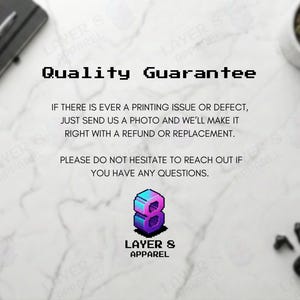 May include: A promotional image with the text "Quality Guarantee" in a pixelated font. The text promises refunds or replacements for printing issues. The Layer 8 Apparel logo is also visible, along with a notebook, pen, plant, and wireless earbuds.
