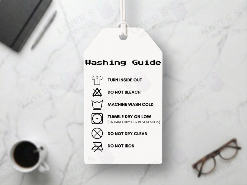 May include: A white tag with a washing guide, including instructions to turn inside out, not bleach, machine wash cold, tumble dry on low, not dry clean, and not iron. The tag is hanging on a white string.