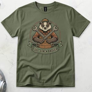 Military green Gildan 64000 t-shirt featuring a vintage mechanic mascot illustration of a grumpy badger wearing overalls and holding two crossed wrenches above the text "FULL-STACK BADGER" on a green banner.