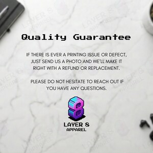May include: A promotional image with the text "Quality Guarantee" in a pixelated font. The text promises refunds or replacements for printing issues. The Layer 8 Apparel logo is featured, along with a notebook, pen, plant, and wireless earbuds.