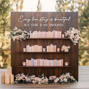 Peut inclure: Un fond en bois avec trois étagères présentant des livres aux couleurs pastel. Le texte "Every love story is beautiful BUT OURS IS MY FAVOURITE" est écrit en blanc. Des compositions florales et des bougies ornent le décor.