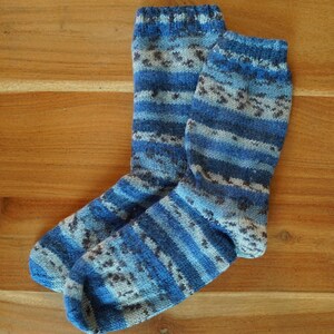 Pode incluir: Um par de meias de malha em tons de azul, cinza e branco. As meias apresentam um padr&atilde;o listrado e salpicado, com punho e calcanhar canelados. As meias s&atilde;o feitas de um material macio e quente.